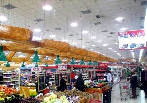 Intérieur d'épicerie bien éclairé avec produits frais et clients. La lumière naturelle améliore l'expérience d'achat.