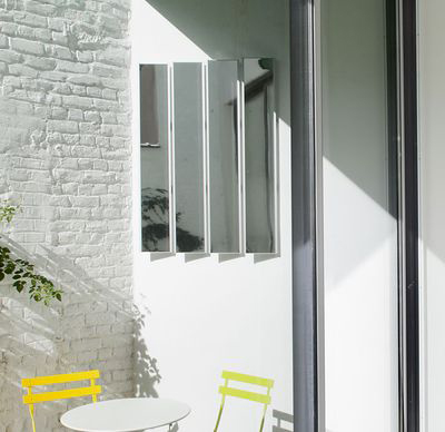Patio moderne avec chaises jaunes et réflecteur lumineux à quatre panneaux.