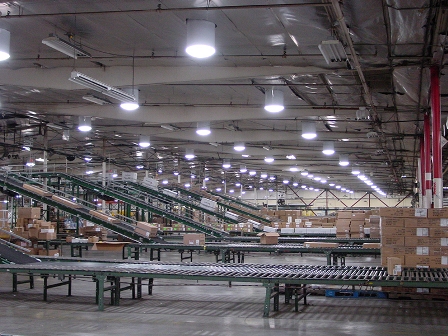 Intérieur d'entrepôt moderne avec solution d'éclairage naturel efficace de Solatube et système de convoyeur pour le stockage et la gestion des stocks.