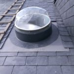 Conduit de lumière installé sur une toiture en ardoise.