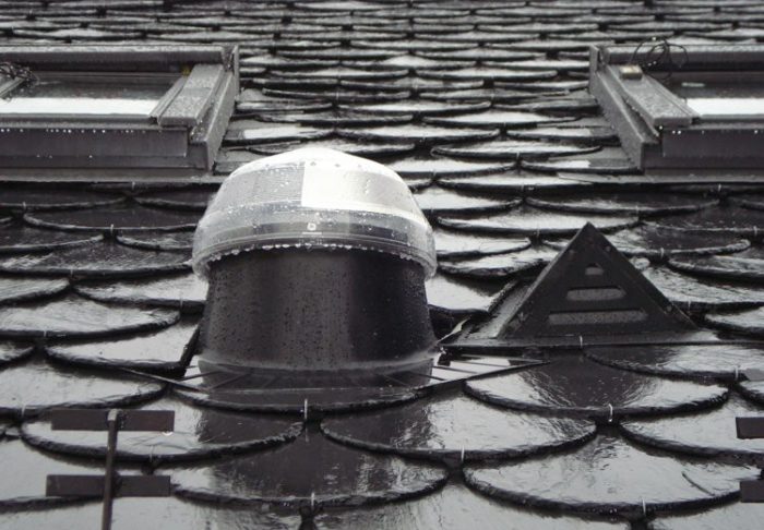 conduit de lumière solatube et deux fenêtres de toit installés sur une toiture en ardoise. La lumière solaire pénètre par un dôme.