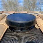 Ventilateur de grenier à énergie solaire installé sur un toit en tuiles.