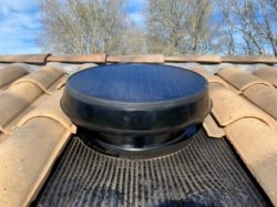 Ventilateur de grenier à énergie solaire installé sur un toit en tuiles.