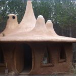 Maison insolite en terre avec conduits de lumière naturels dans une forêt.